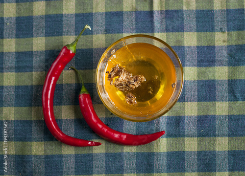 liquid honey with honeycombs in a glass bowl with  chilli paper on  tableclothes photo