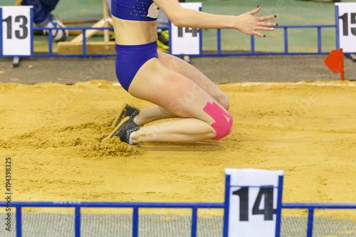 Sportswoman landing into sandpit on training in long jump. Track and field competitions concept background