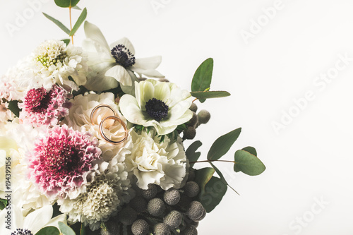 Photo close up view of wedding rings in bridal bouquet isolated on white