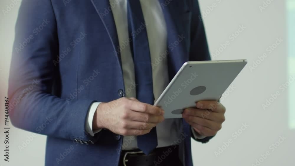 Mid-section of unrecognizable businessman in suit holding tablet Mid-section of unrecognizable businessman in suit holding tablet