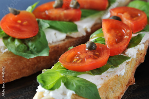 baguette with soft cheese, basil, cherry tomatoes, capers