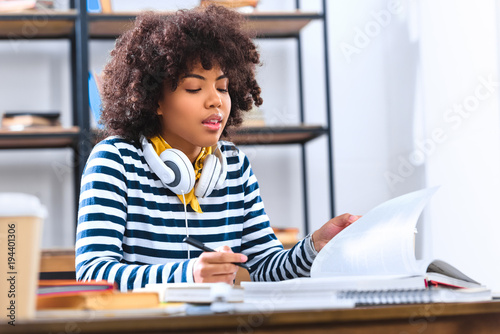 african american student with headphones studying alone