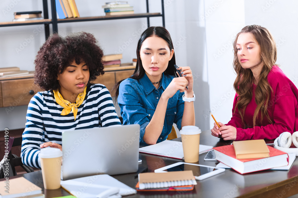 portrait of multiethnic young students using laptop while studying together