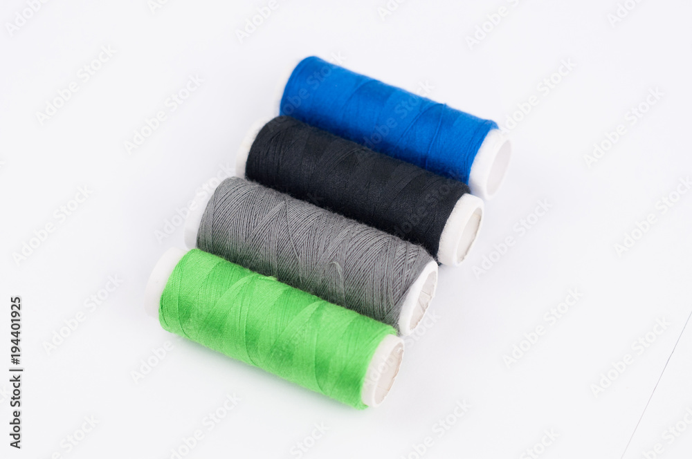 Four bobbins of new colorful threads on white background Four bobbins of new colorful threads on white background