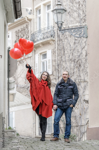 love story. A young man and a young woman with red accessories are walking in the city