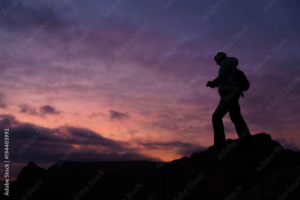 Silhouette of a person taking photo of a sunset with purple background