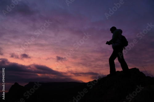 Silhouette of a person taking photo of a sunset with purple background