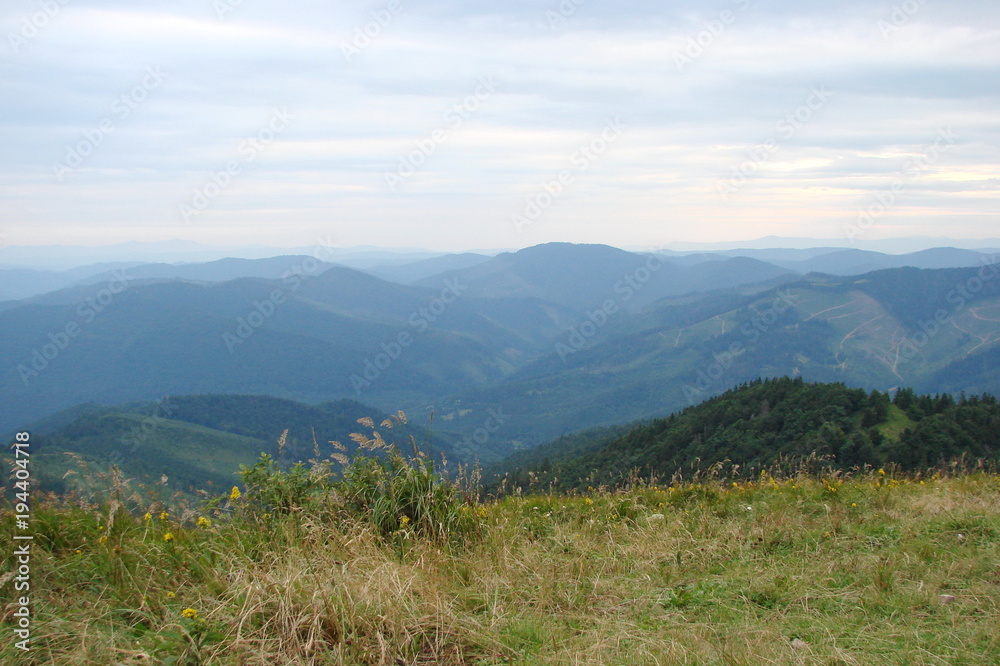 The landscape of the Ukrainian Carpathians against the background of the evening cloudy sky from the height of the highest peak of the mountain range.