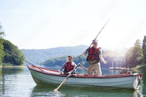 Senior man with son fishing in lake