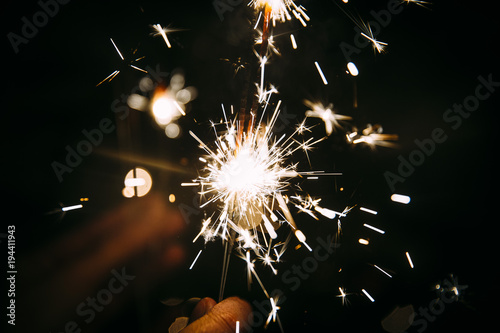Burning Sparkler in  a party with moody bokeh in the background