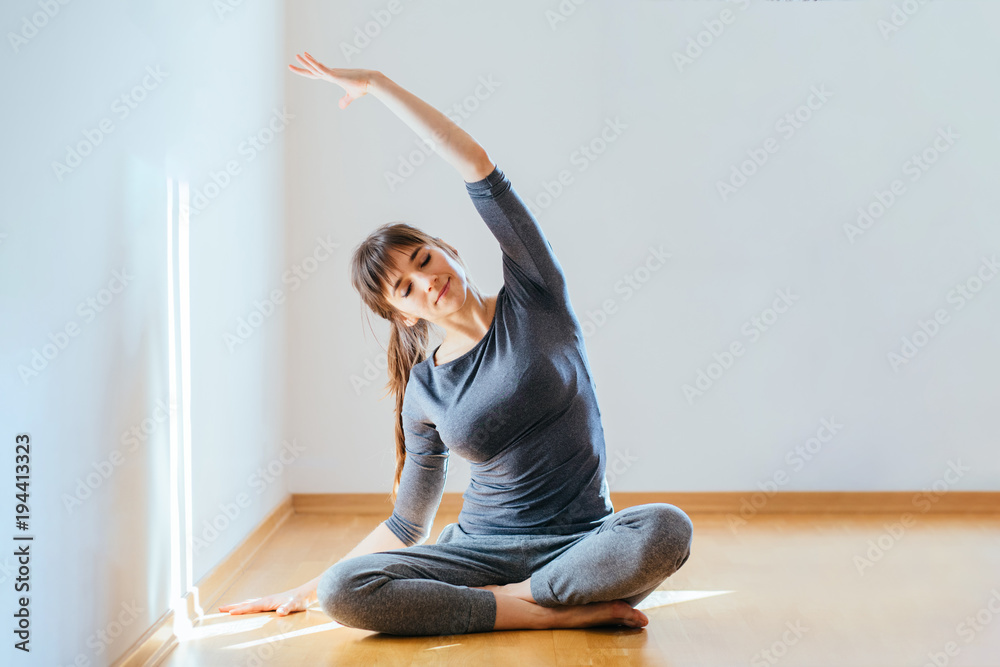 yoga candid Front view full body portrait of a relaxed candid caucasian woman  practicing yoga sitting on the floor in the empty living room at home. New  day, morning routine concept. Stock Photo |
