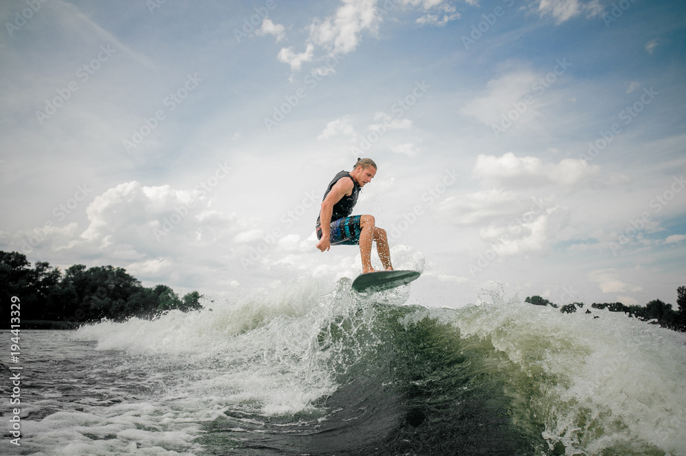 Wakesurf rider jumping on the waves of a river