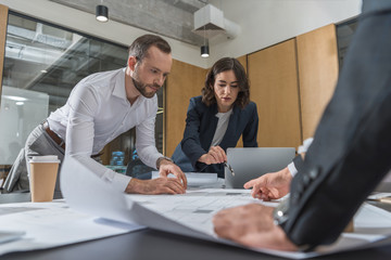 team of architects brainstorming on building plans at modern office