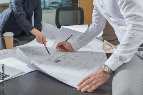 cropped shot of stylish architects working with building plans together at office photo