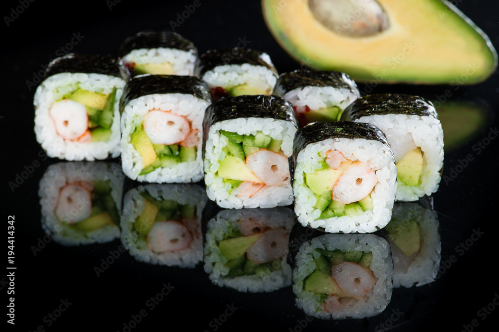 Japanese cuisine. Appetizing maki sushi rolls with rice, avocado, cucumber and shrimp on dark background Japanese cuisine. Appetizing maki sushi rolls with rice, avocado, cucumber and shrimp on dark background