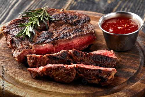 Foto Juicy steak medium rare beef with spices on wooden board on table