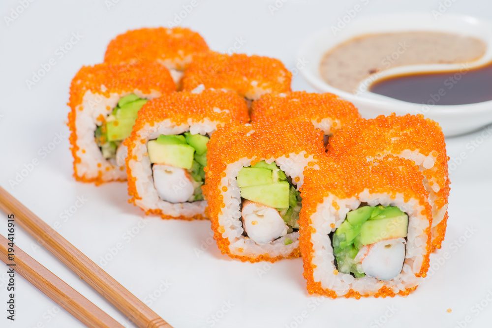 Appetizing California sushi rolls with rice, shrimps, avocado, cucumber and tobiko on light background