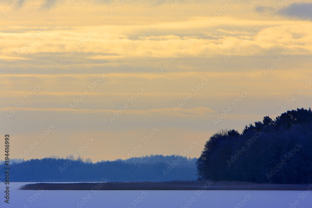 Winter landscape with frozen lake surface and woods in Masuria lakes district in Poland - Lasmiady lake near town of Elk