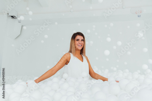 Portrait Happy woman stand surrounded by white plastic balls in the dry pool. Copy splace. photo