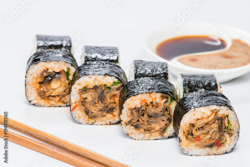 Japanese cuisine. Appetizing maki sushi rolls with rice, mushrooms, sauce and onion on light background