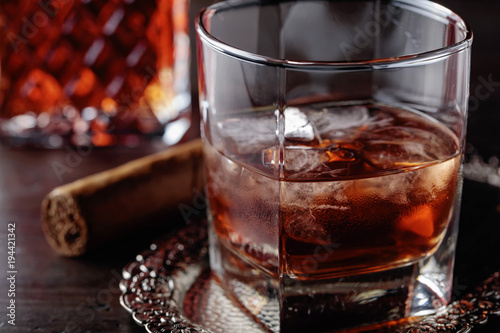 Glass of whiskey and cigar on old wooden table.