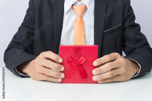 Businessman holds out the gift red box, isolated background