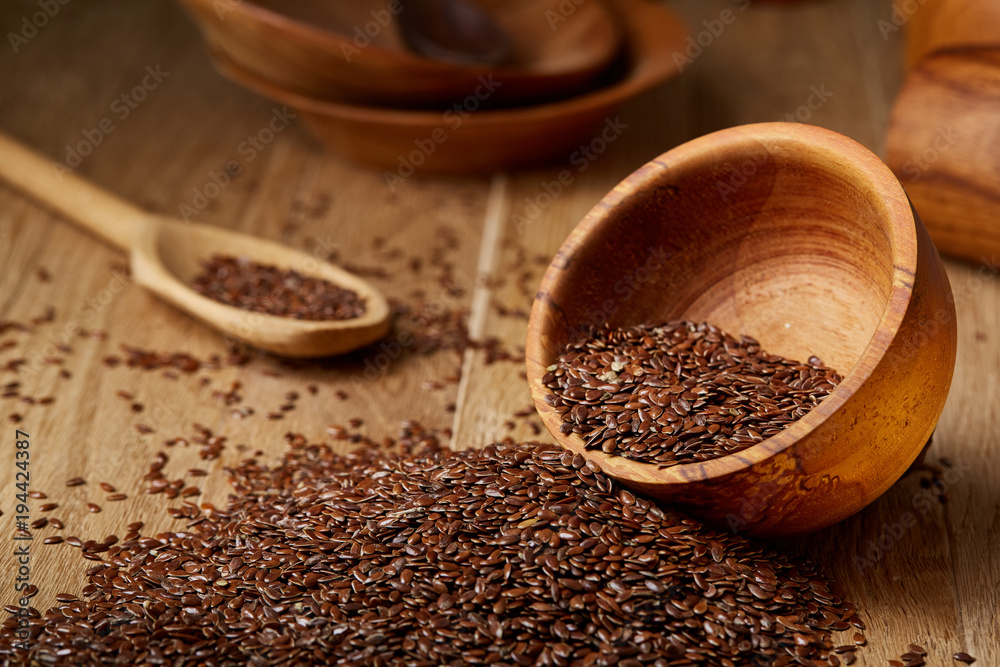 An overturned wooden bowl with linseeds on a rustic background, close-up, shallow depth of field, selective focus An overturned wooden bowl with linseeds on a rustic background, close-up, shallow depth of field, selective focus