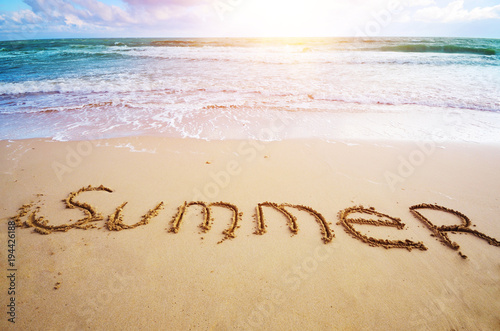 Word Summer written on sand at ocean beach summer time