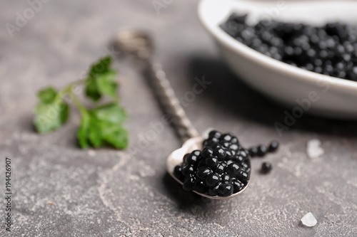 Spoon with delicious black caviar on grey background