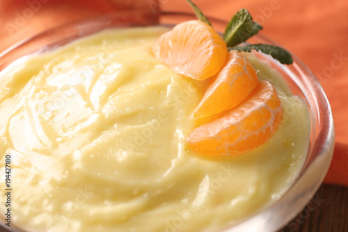 Tasty vanilla pudding with tangerine in bowl, closeup