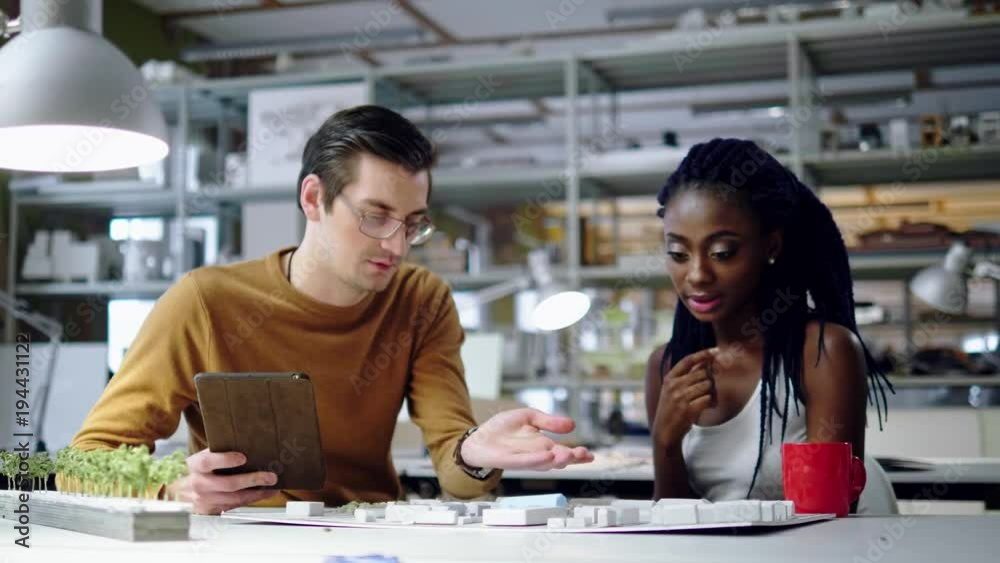 Multiracial couple working in design and engineering architecture office.