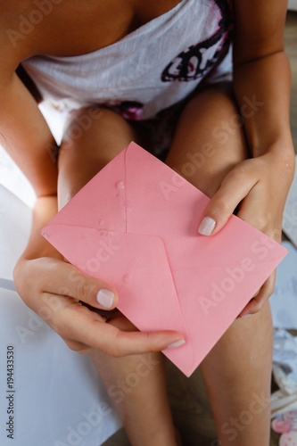 Close-up, holding a tear-stained letter on her knees sad young woman with long hair sitting on the floor. The concept of depression, separation, loss of loved ones. The letter was wet with tears.