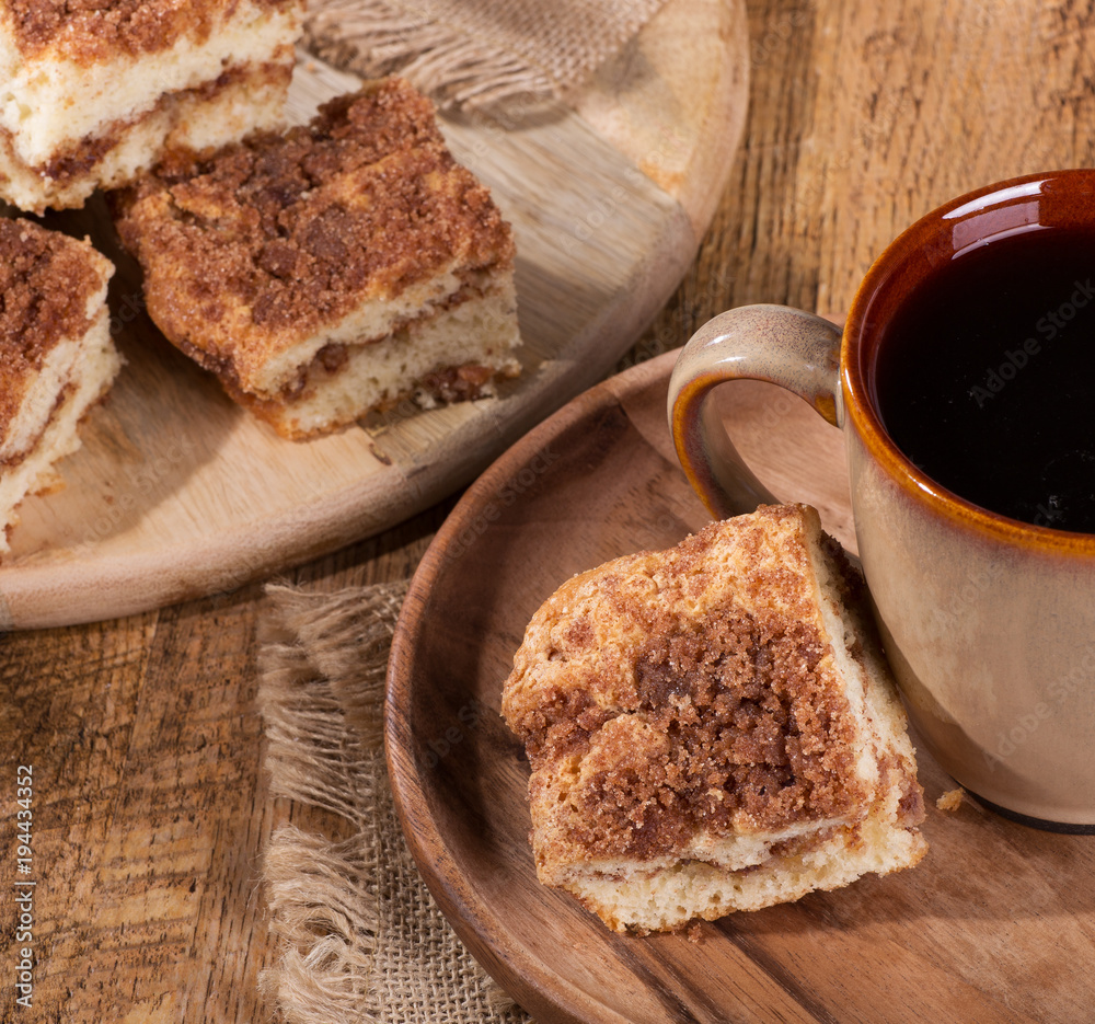 Cinnamon swirl crumb cake and cup of coffee on a wooden plate Cinnamon swirl crumb cake and cup of coffee on a wooden plate