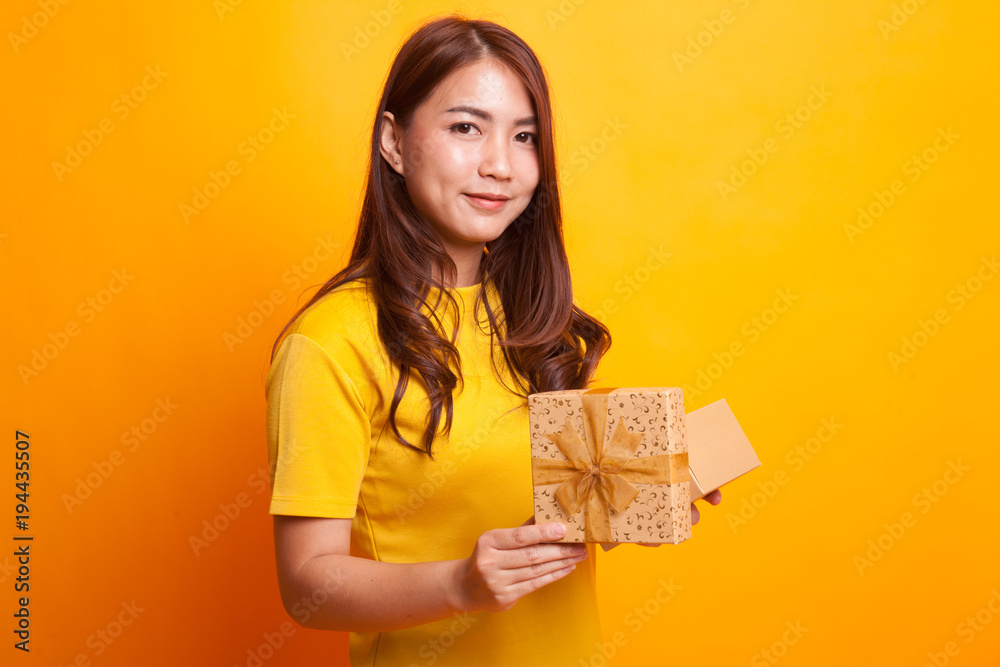 Young Asian woman open a golden gift box. Young Asian woman open a golden gift box.