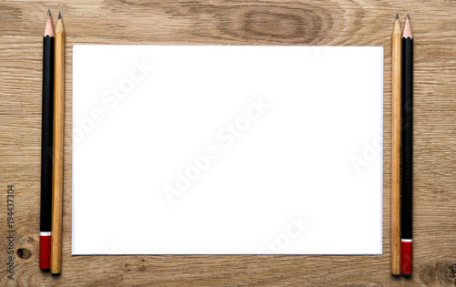 A frame of pencils and a sheet of white paper on a wooden table