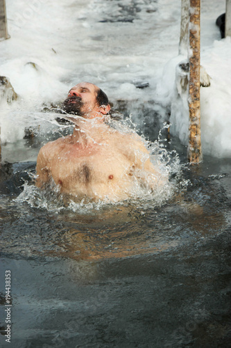 A middle-aged man is immersed in an ice hole.