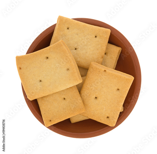 Top view of several hard bread crackers in a small red clay bowl isolated on a white background.