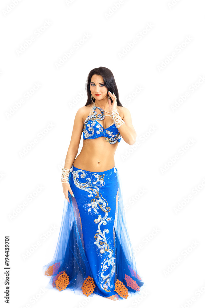 A young dancer in blue clothes performs an oriental belly dance. Isolate. Beautiful girl in bright national clothes dancing on white background. A young dancer in blue clothes performs an oriental belly dance. Isolate. Beautiful girl in bright national clothes dancing on white background.