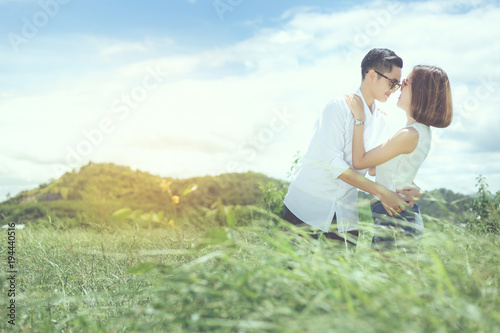 Women lovers are holding together and try to kiss for shooting a photo between travel in natural grass.