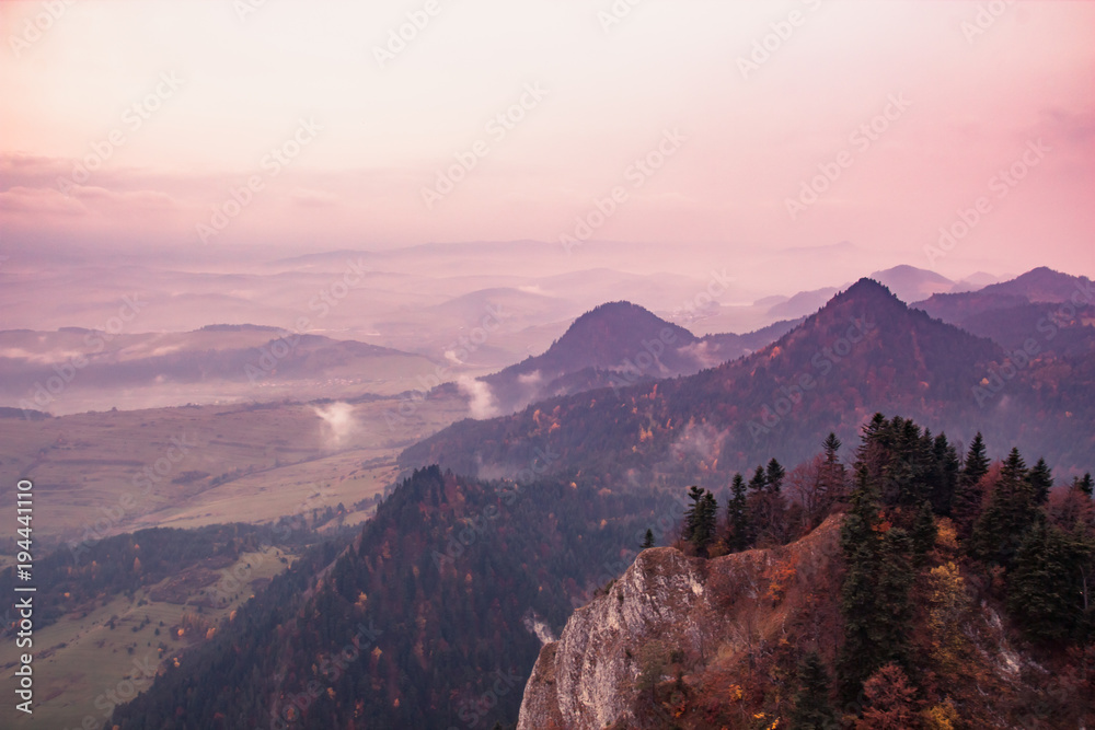 Fantastic mountain landscape, surreal pink and purple sky, the mountains are covered with trees