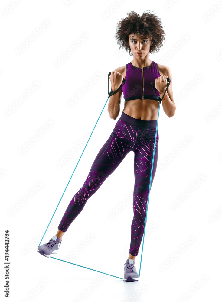 Young girl performs exercises using expander. Photo of muscular african girl isolated on white background. Strength and motivation. Full length Young girl performs exercises using expander. Photo of muscular african girl isolated on white background. Strength and motivation. Full length