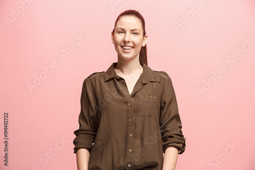 The happy business woman standing and smiling against pink background.