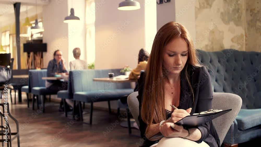 Young busisnesswoman doing notes in cafe

