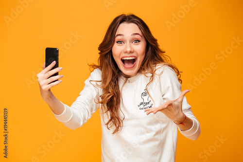 Excited screaming young woman using mobile phone.