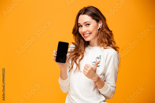 Φωτογραφία Emotional young woman listening music showing mobile phone