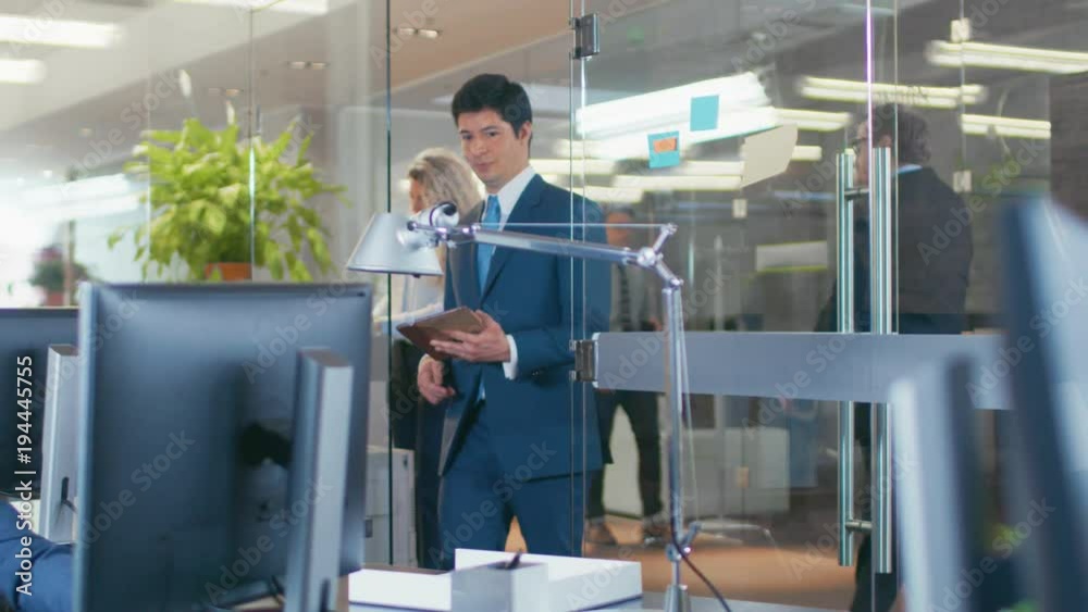 In the Big Office Businessman Walks into Glass Office and Shows Tablet Computer to His Colleague. Shot on RED EPIC-W 8K Helium Cinema Camera. In the Big Office Businessman Walks into Glass Office and Shows Tablet Computer to His Colleague. Shot on RED EPIC-W 8K Helium Cinema Camera.