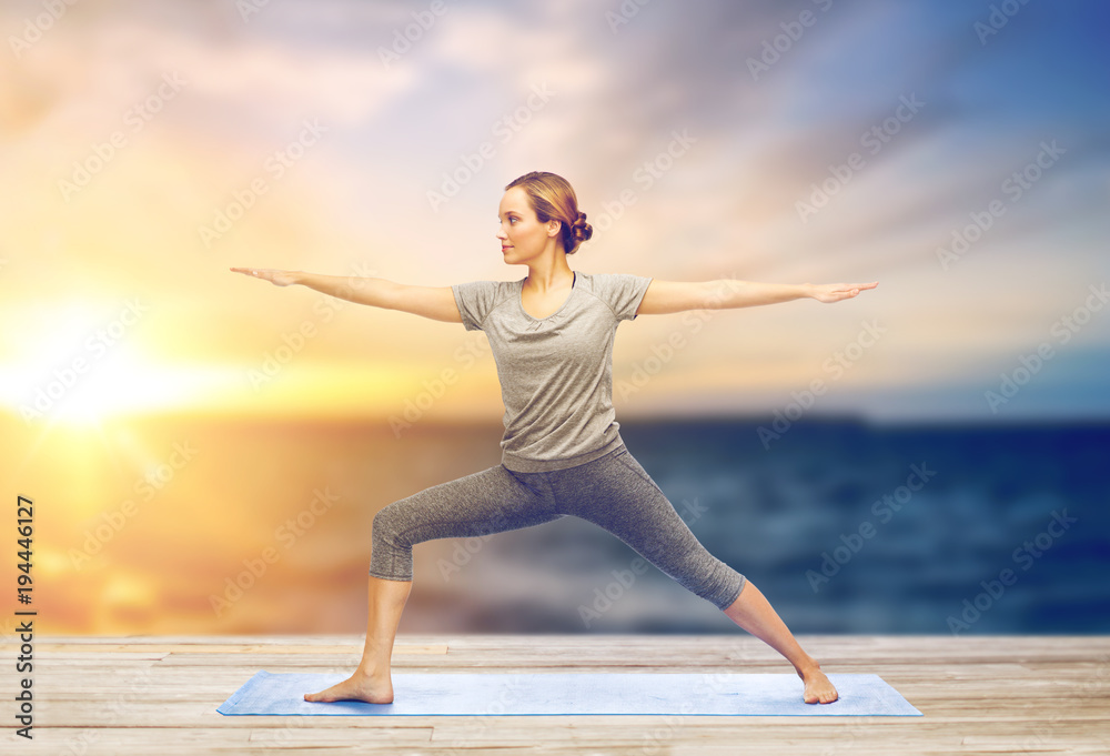 Fototapeta premium woman making yoga warrior pose on mat