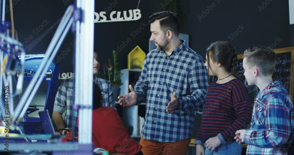 Man conducting class with group of kids having club and discussing robotics and technologies. Movement 4K shot on Red cinema camera.