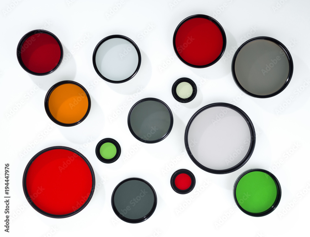 Glass round filters of different colors and sizes are isolated on white background.