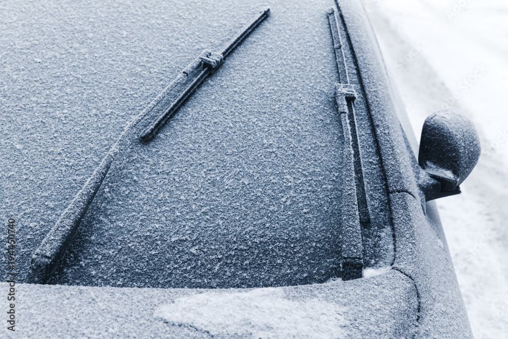 Naklejka premium Car wipers on windshield covered with snow
